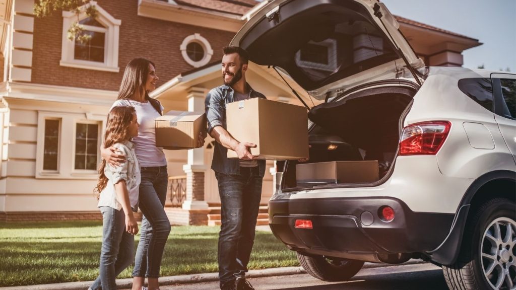 Família colocando caixas em porta malas de carro.