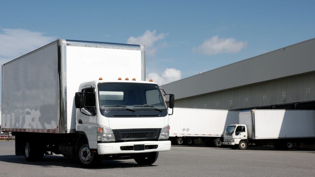 Empresas de frete: caminhão saindo do estacionamento de um galpão