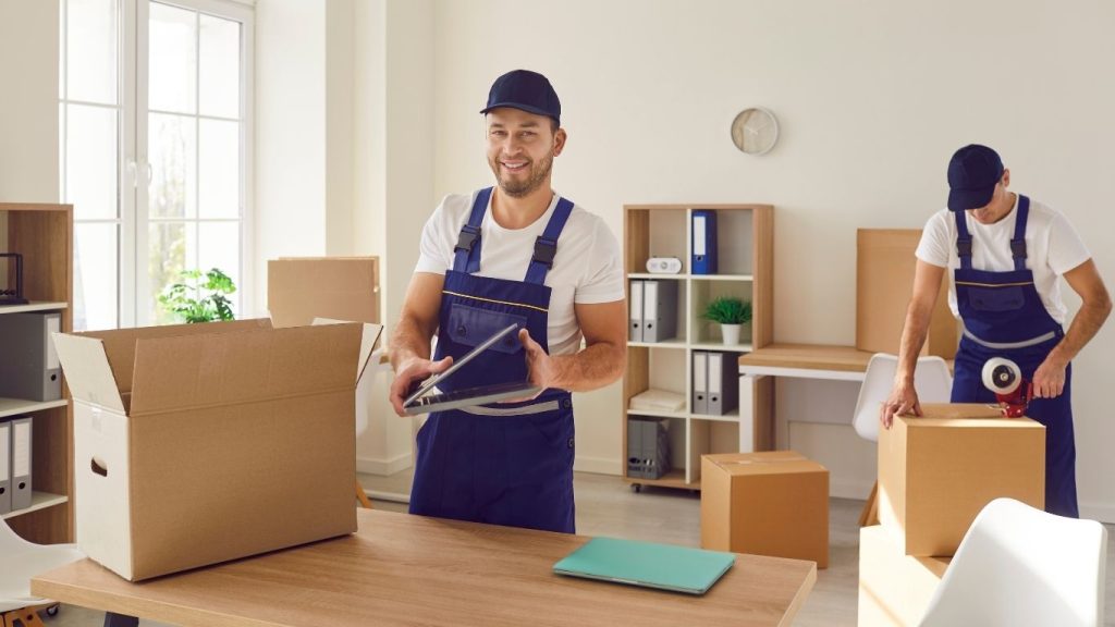 Mudança para outro estado: funcionário de empresa de mudança embalando mudança em caixas.